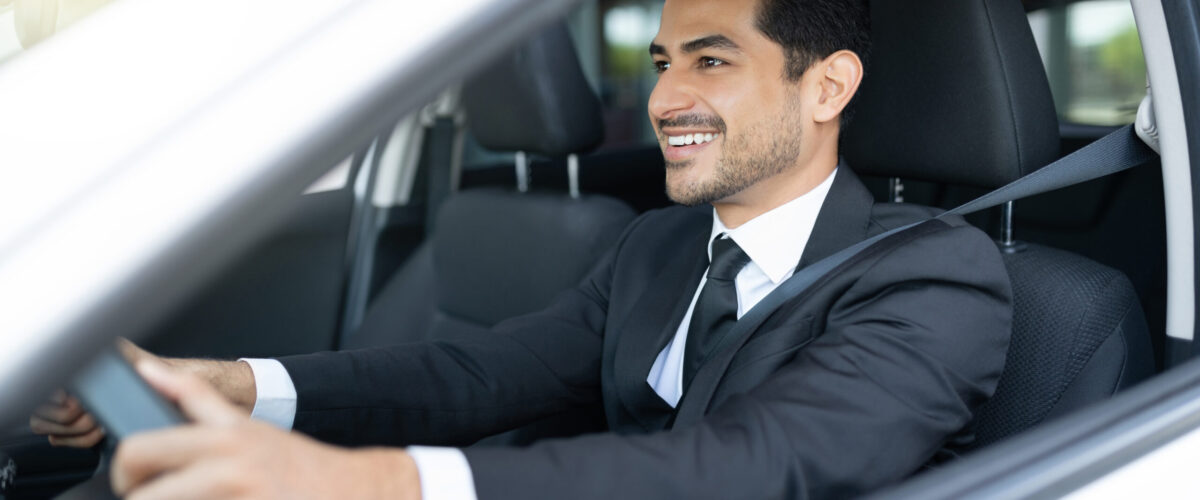 Smiling Latin good looking businessman driving car in city